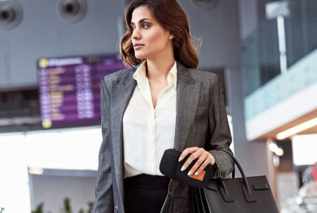 Businesswoman in a terminal wearing the Travola detachable purse on its own, the neoprene bottle sleeve left behind for a lighter carry.